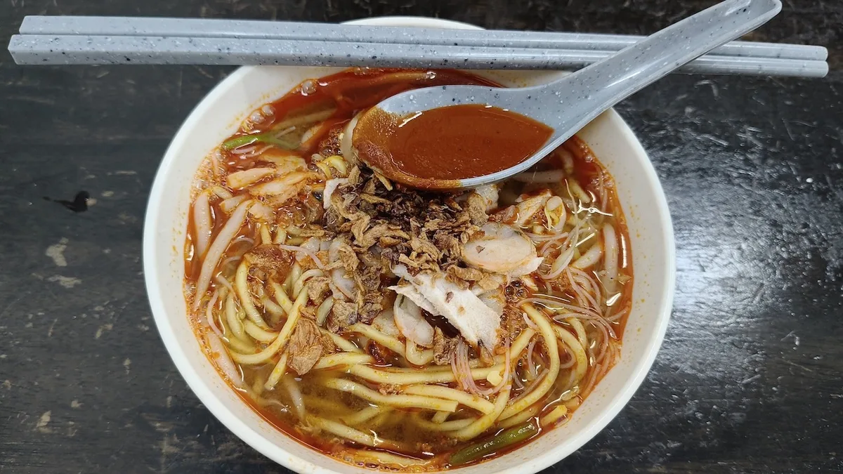 Hokkien mee with prawns, pork slices and fried shallots in red prawn broth