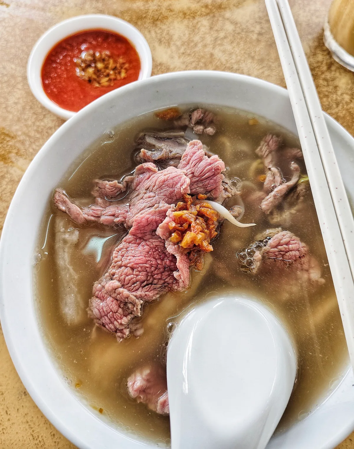 Beef koay teow soup with rare beef slices and chili sauce