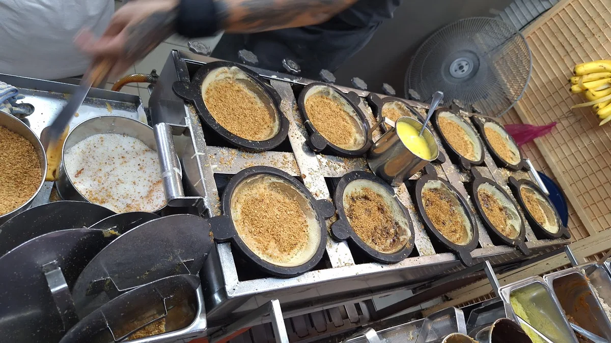 Peanut sugar sprinkled into the pancake moulds on the griddle rack