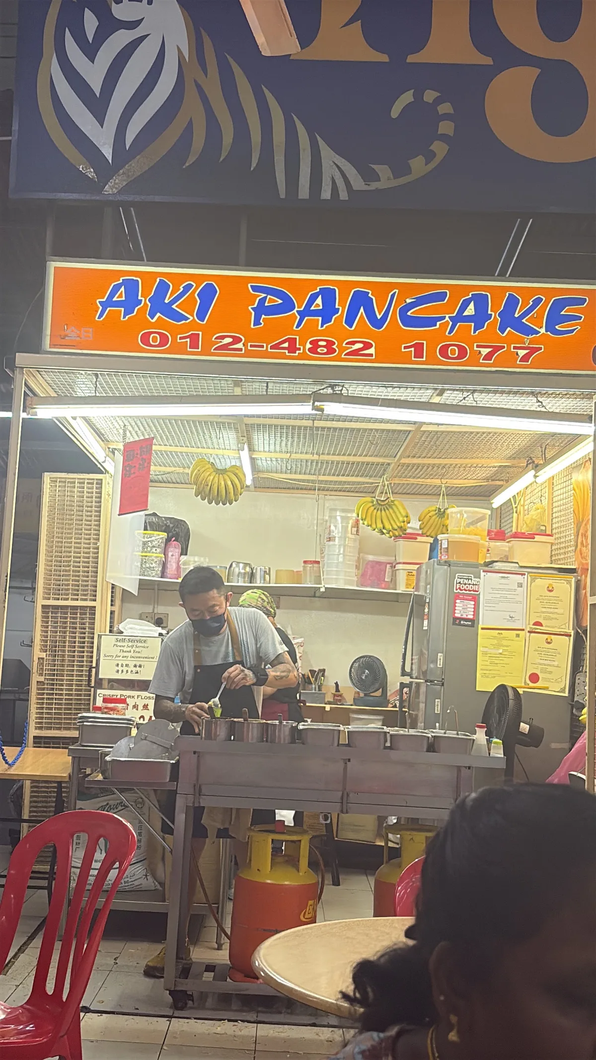 The stall's AKI PANCAKE signboard above the griddle rack