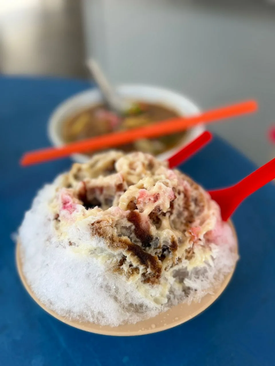 A bowl of shaved ice dessert with syrup and toppings