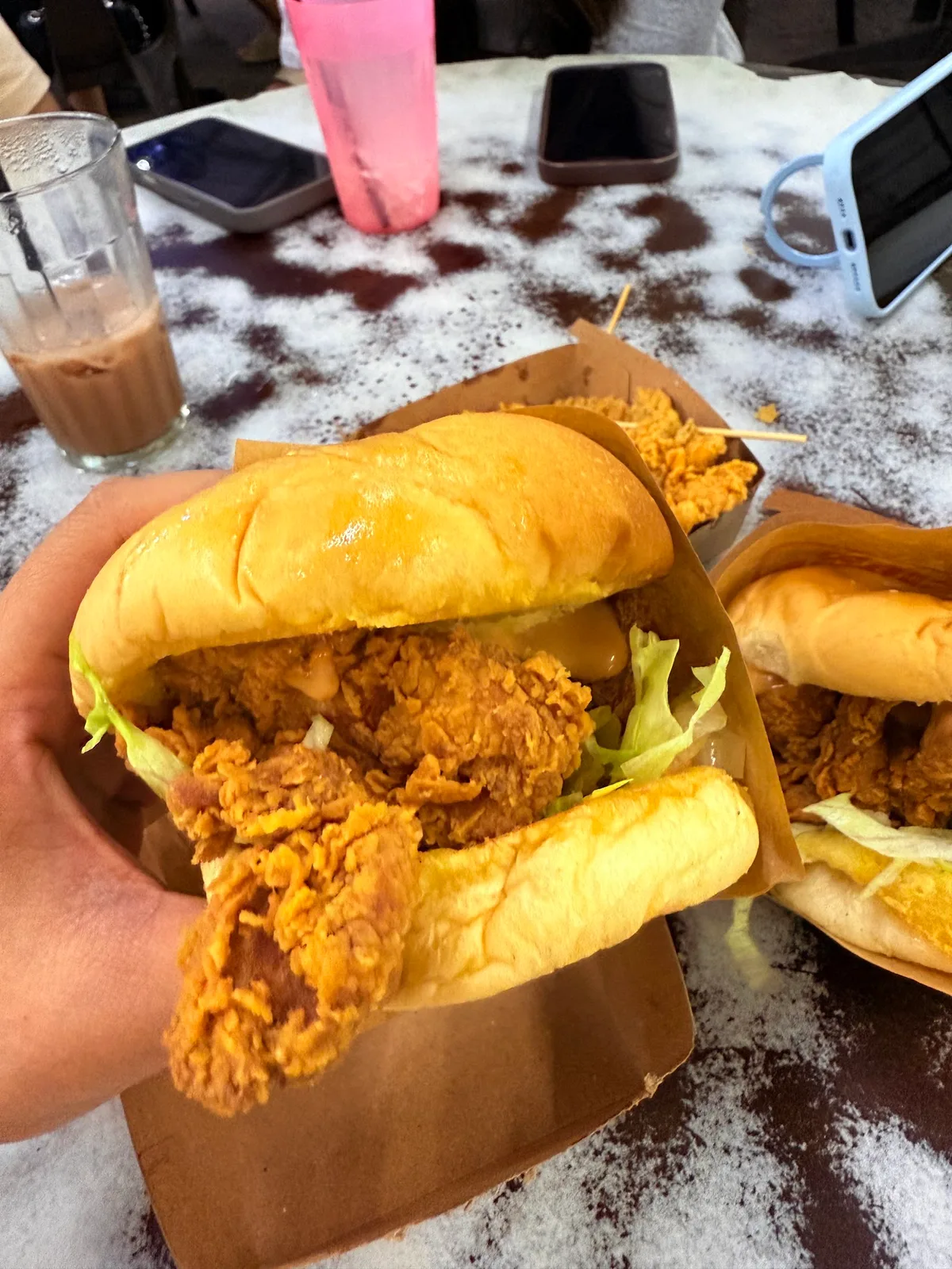 Fried chicken burger held over the table