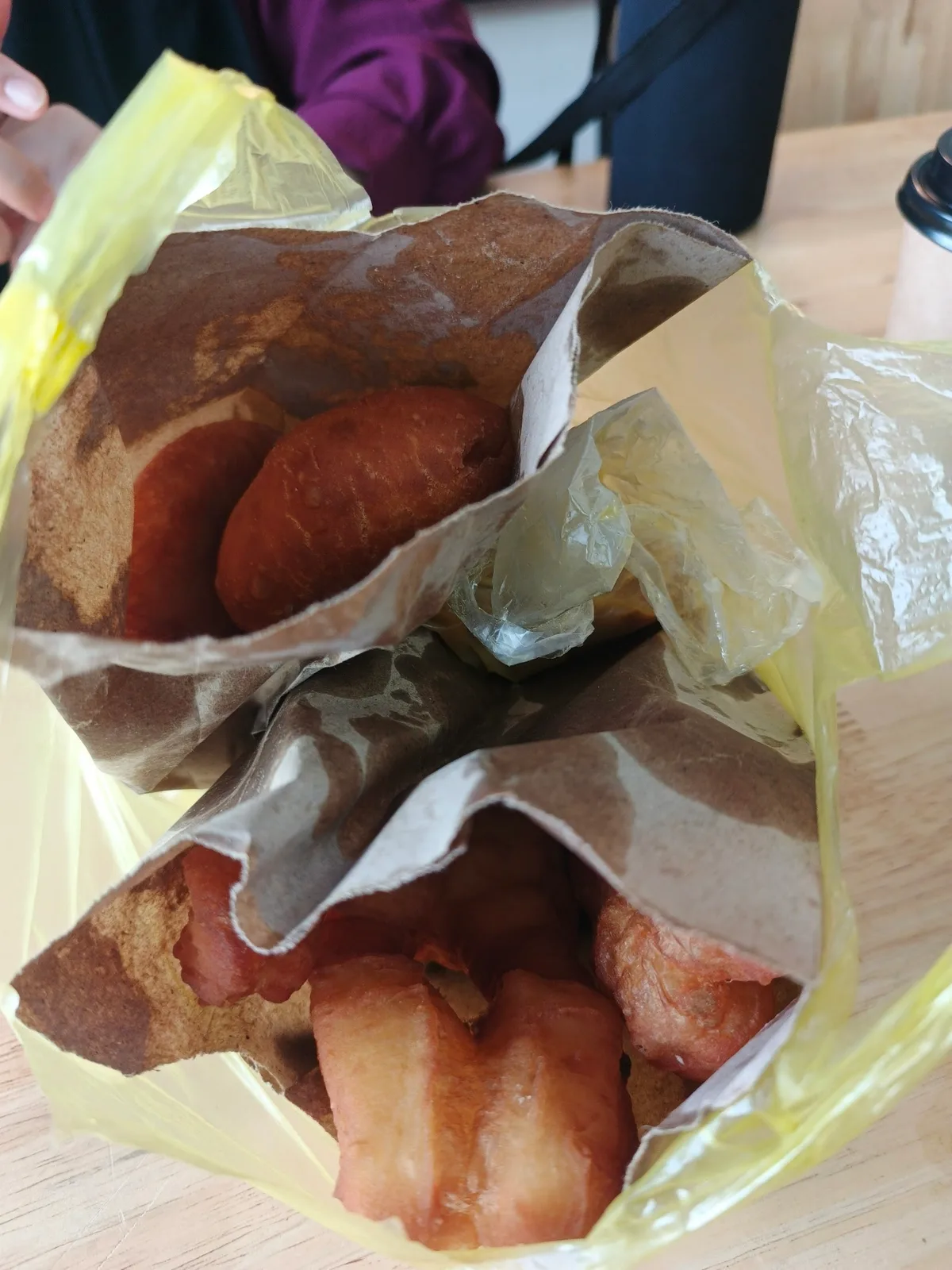 Fried cakoi wrapped in brown paper inside a yellow plastic takeaway bag