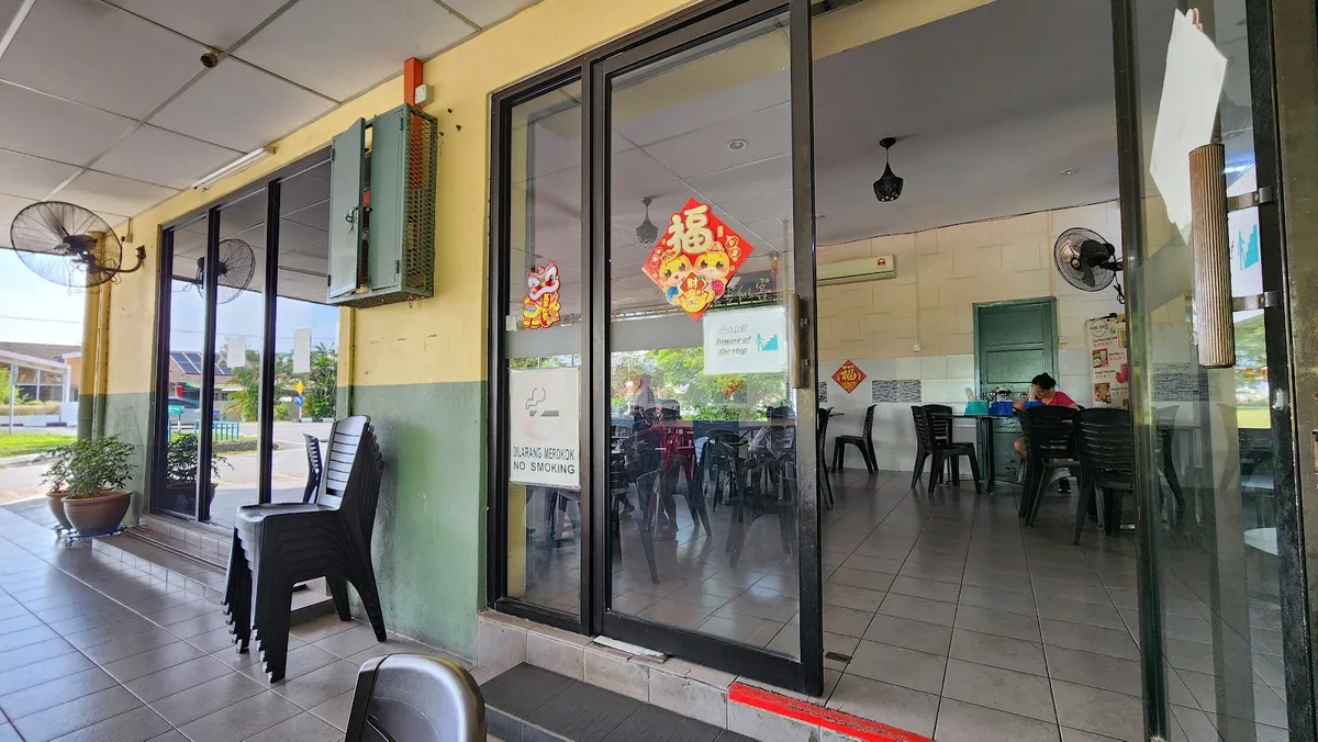 The restaurant's glass sliding front doors and yellow and green facade seen from the covered walkway outside