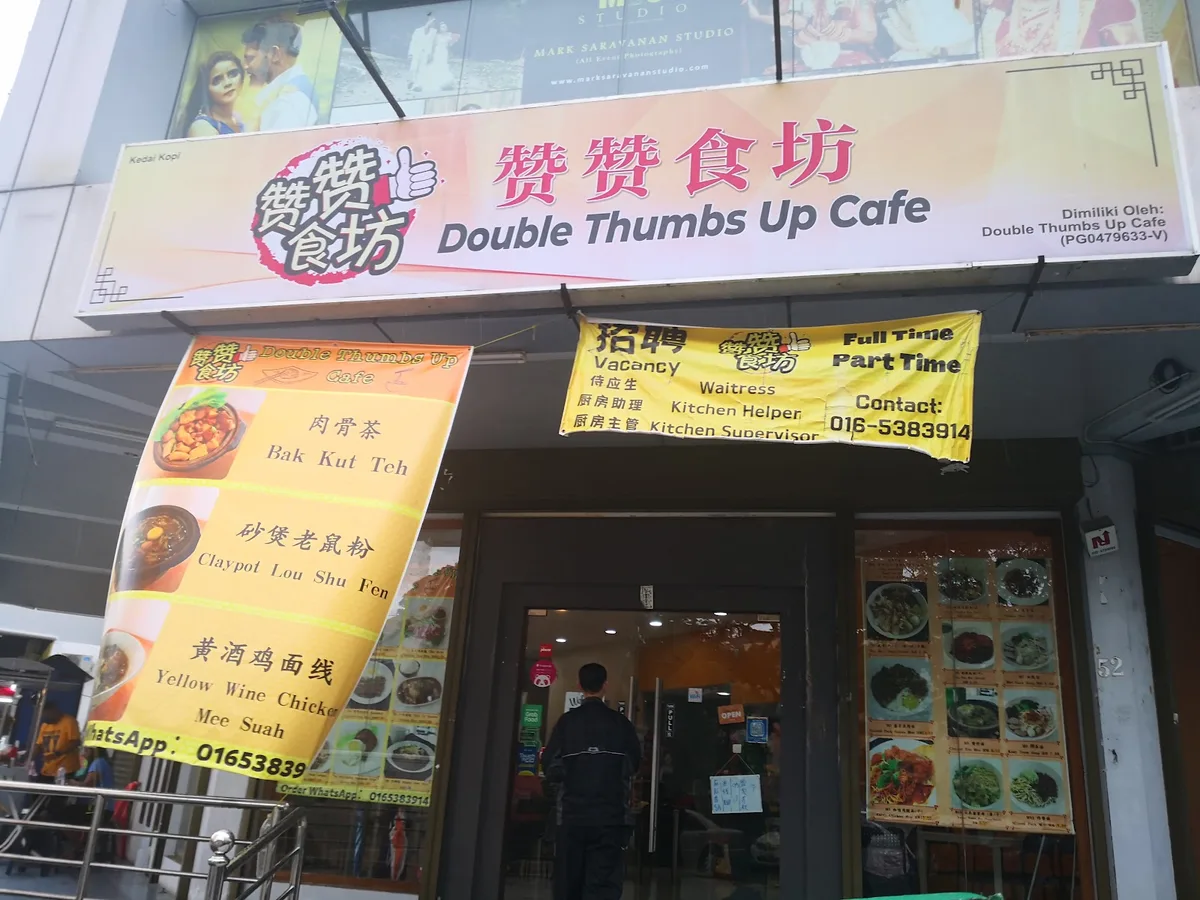 The shopfront under the Double Thumbs Up Cafe signboard, with banners for bak kut teh and claypot lou shu fun
