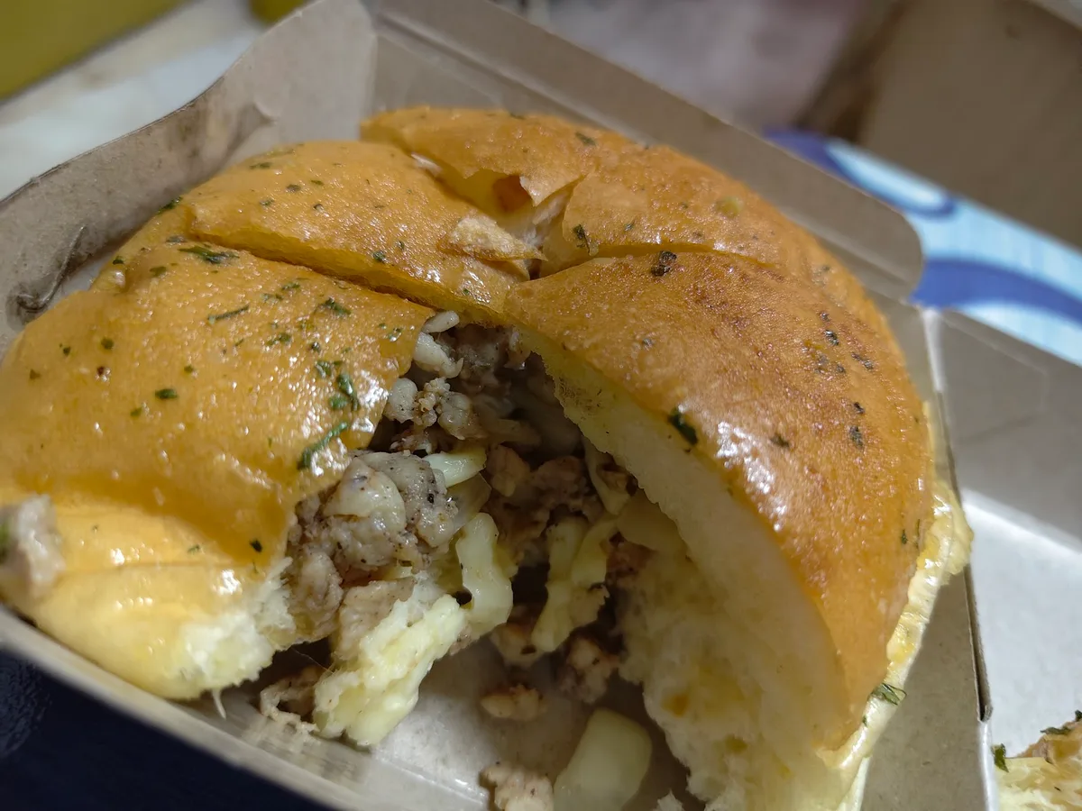 Garlic cheese bun torn open to show the chicken and cheese filling