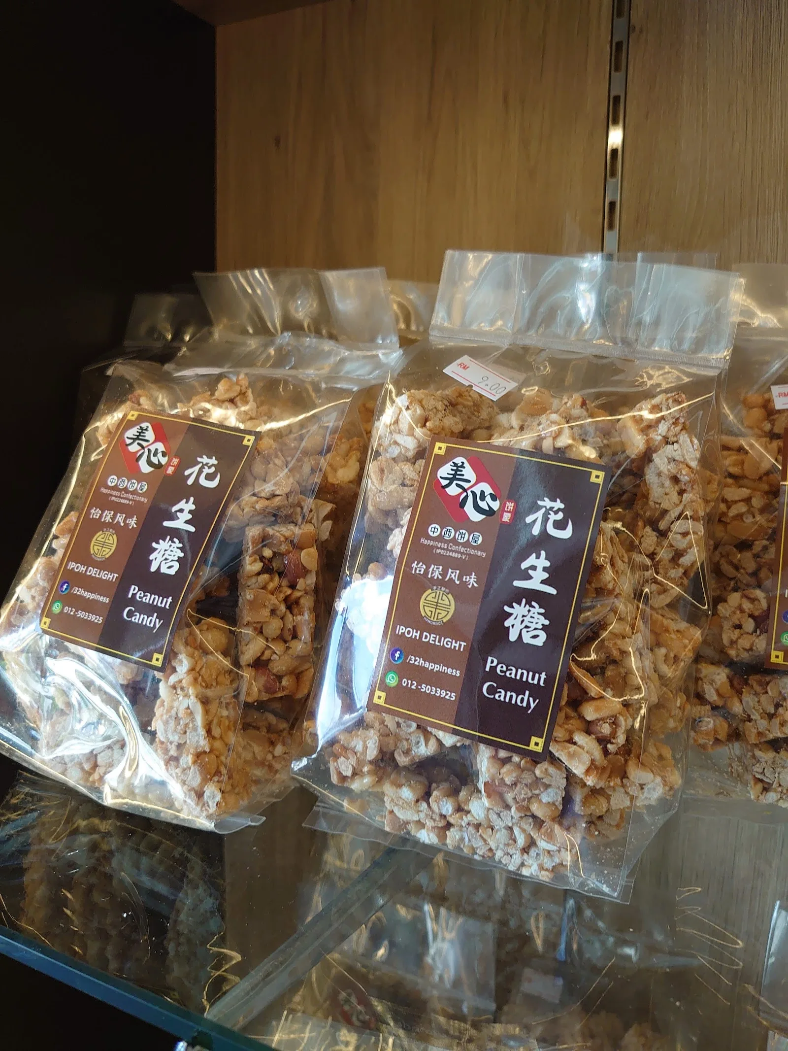 Packets of peanut candy with brown labels stacked on a glass shelf
