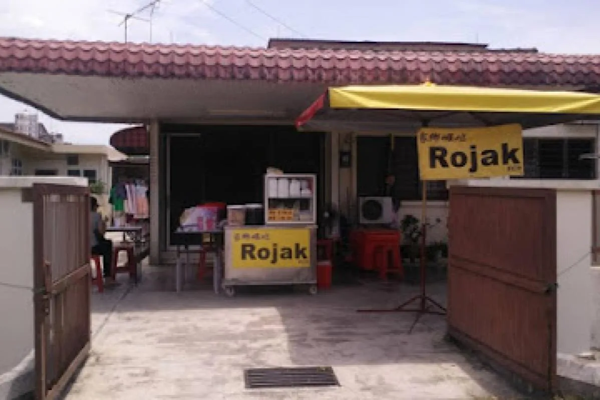 The rojak stall set up in the porch of a terrace house under two yellow Rojak signs
