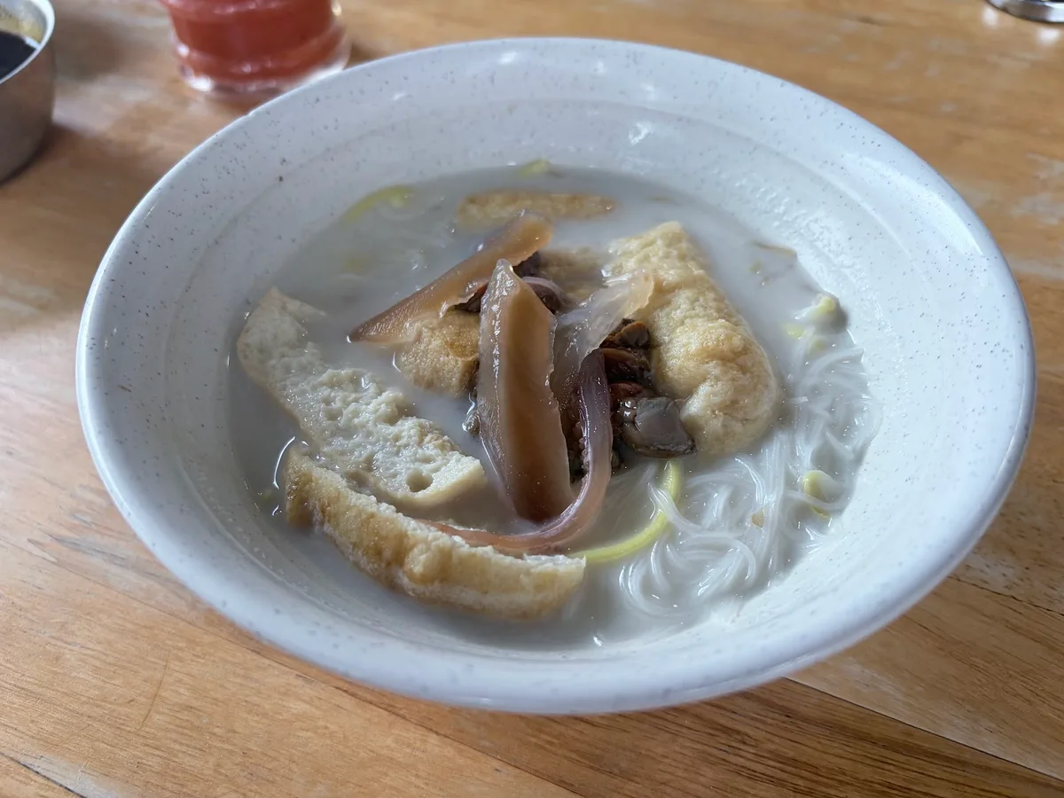 Bowl of white curry mee with cuttlefish and tofu puff