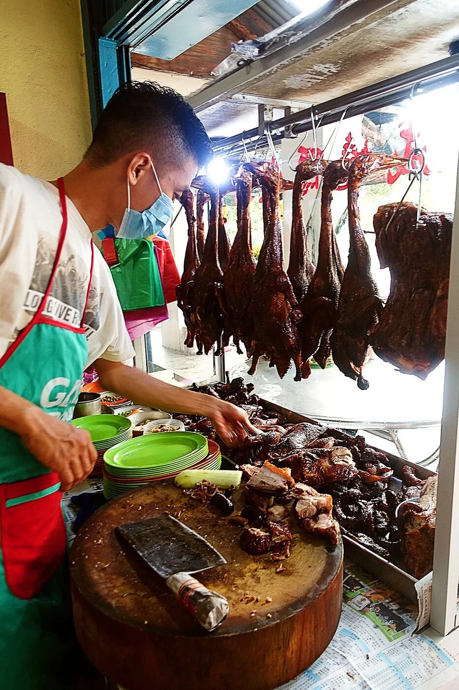 Roast ducks hanging over the chopping block