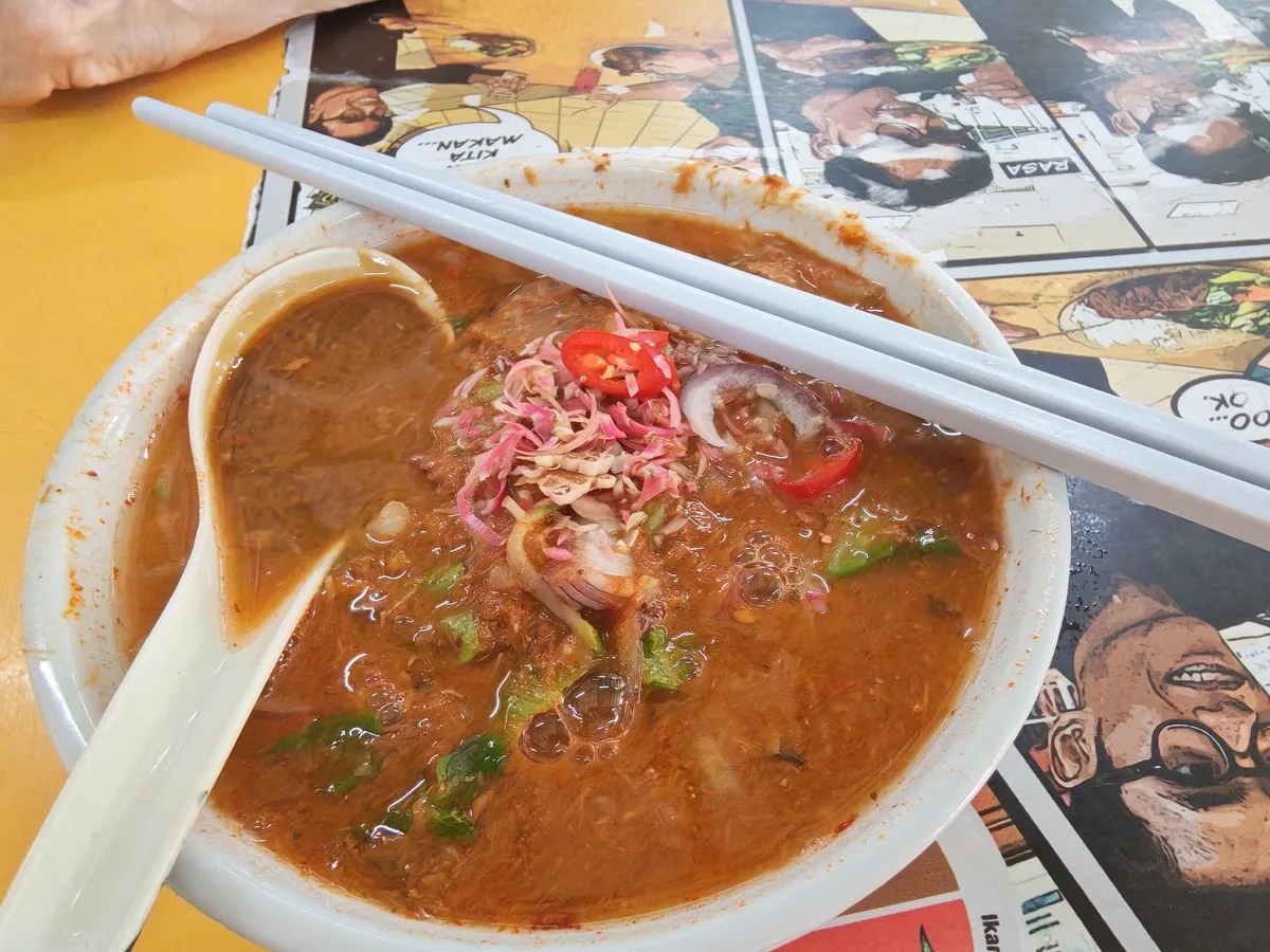 Asam laksa topped with red chilli and prawn paste on the side