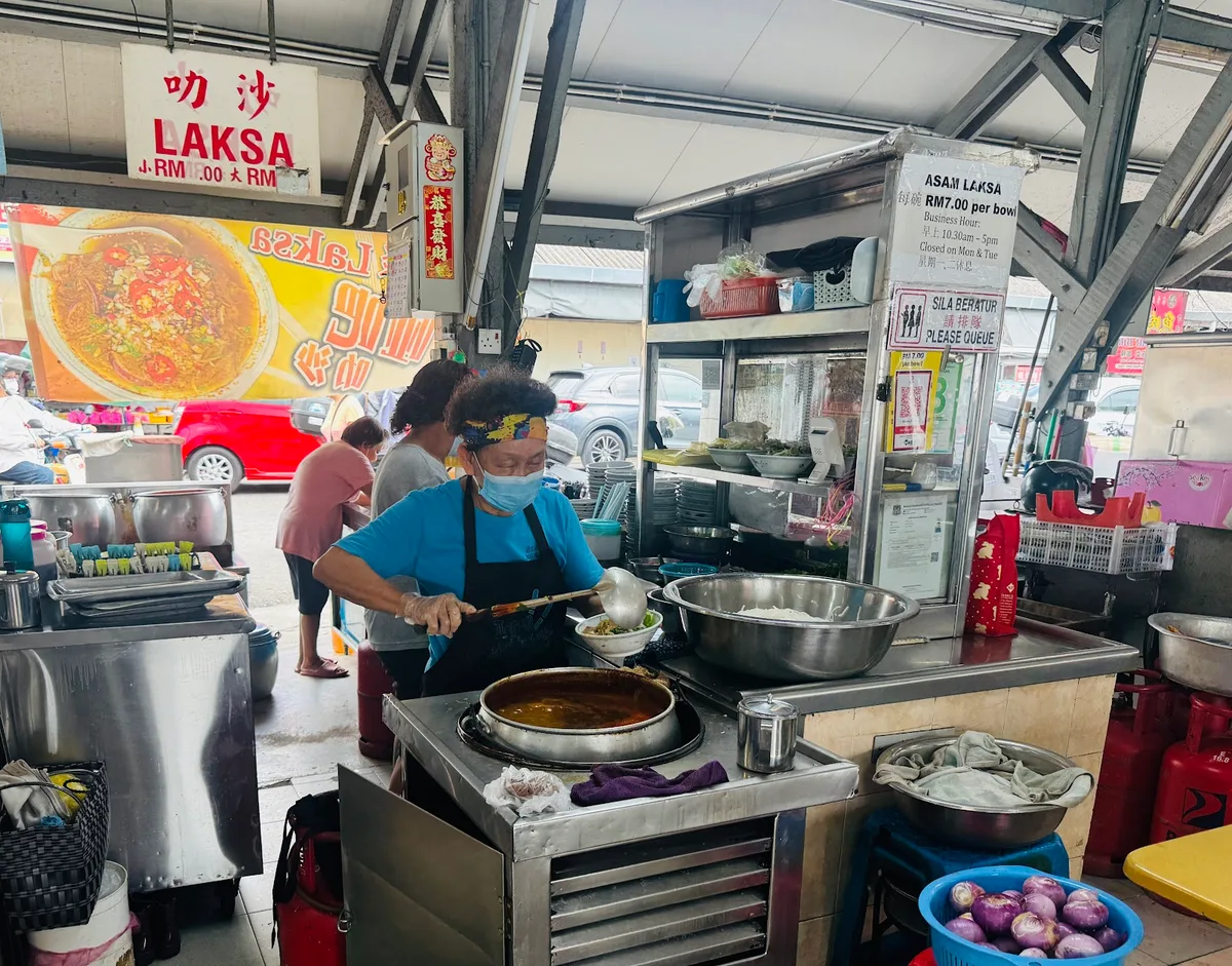Laksa signage above the stall with the cook at the pot