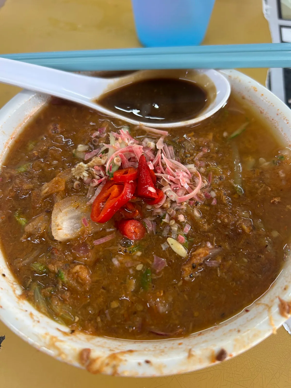 Close-up of the laksa broth with cucumber and onion slivers
