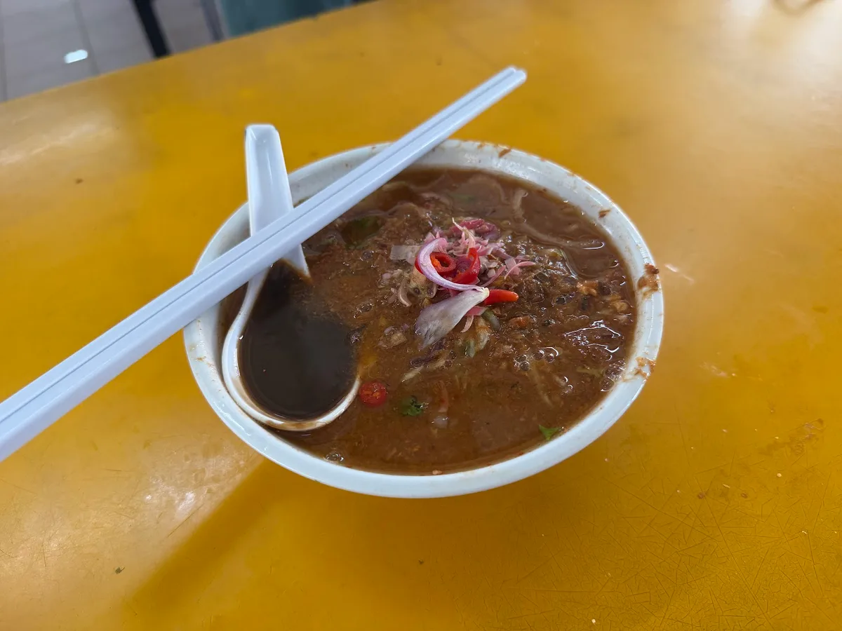 Laksa bowl with the spoon resting in the broth