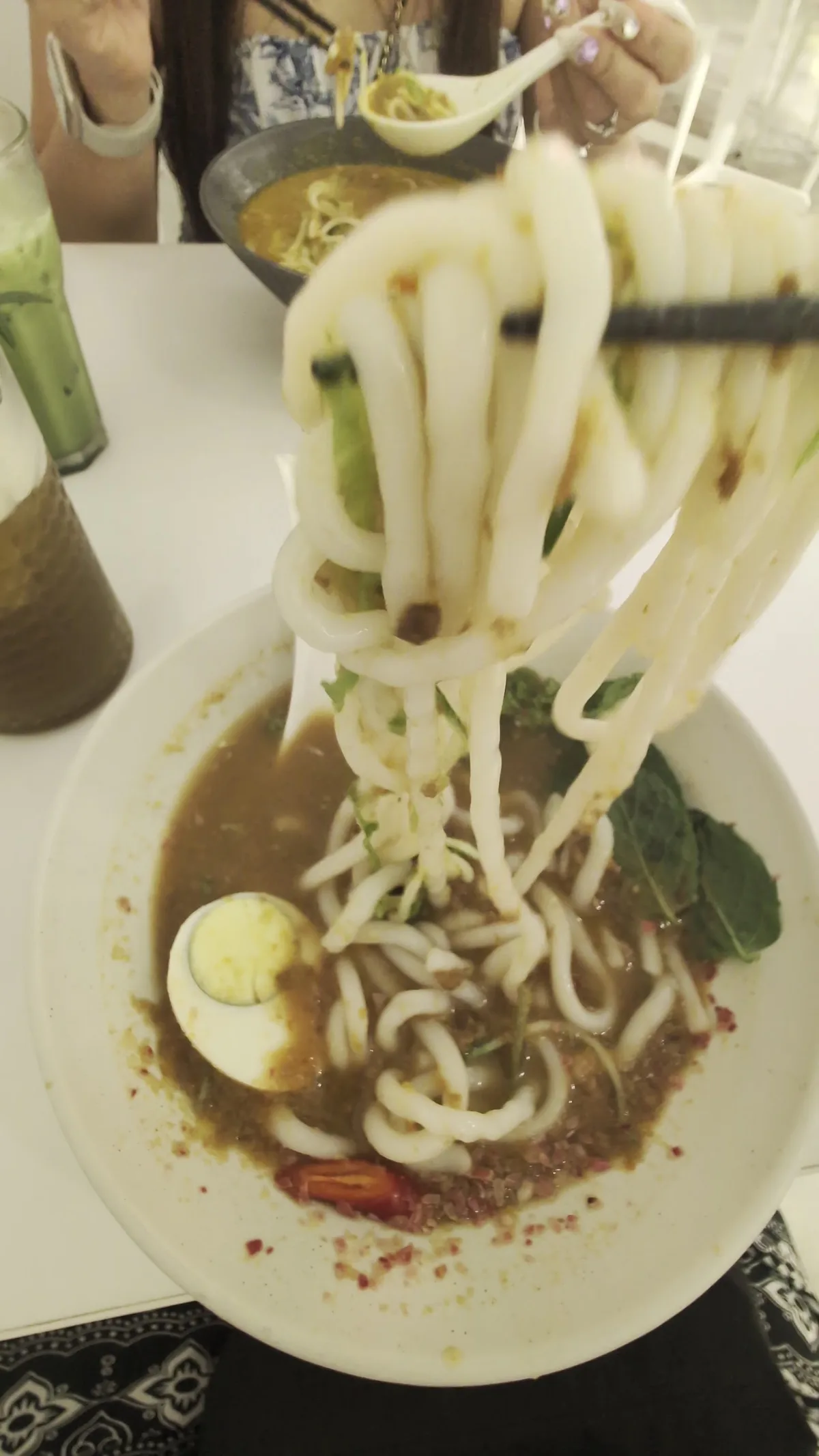 Lifting thick laksa noodles from the asam broth