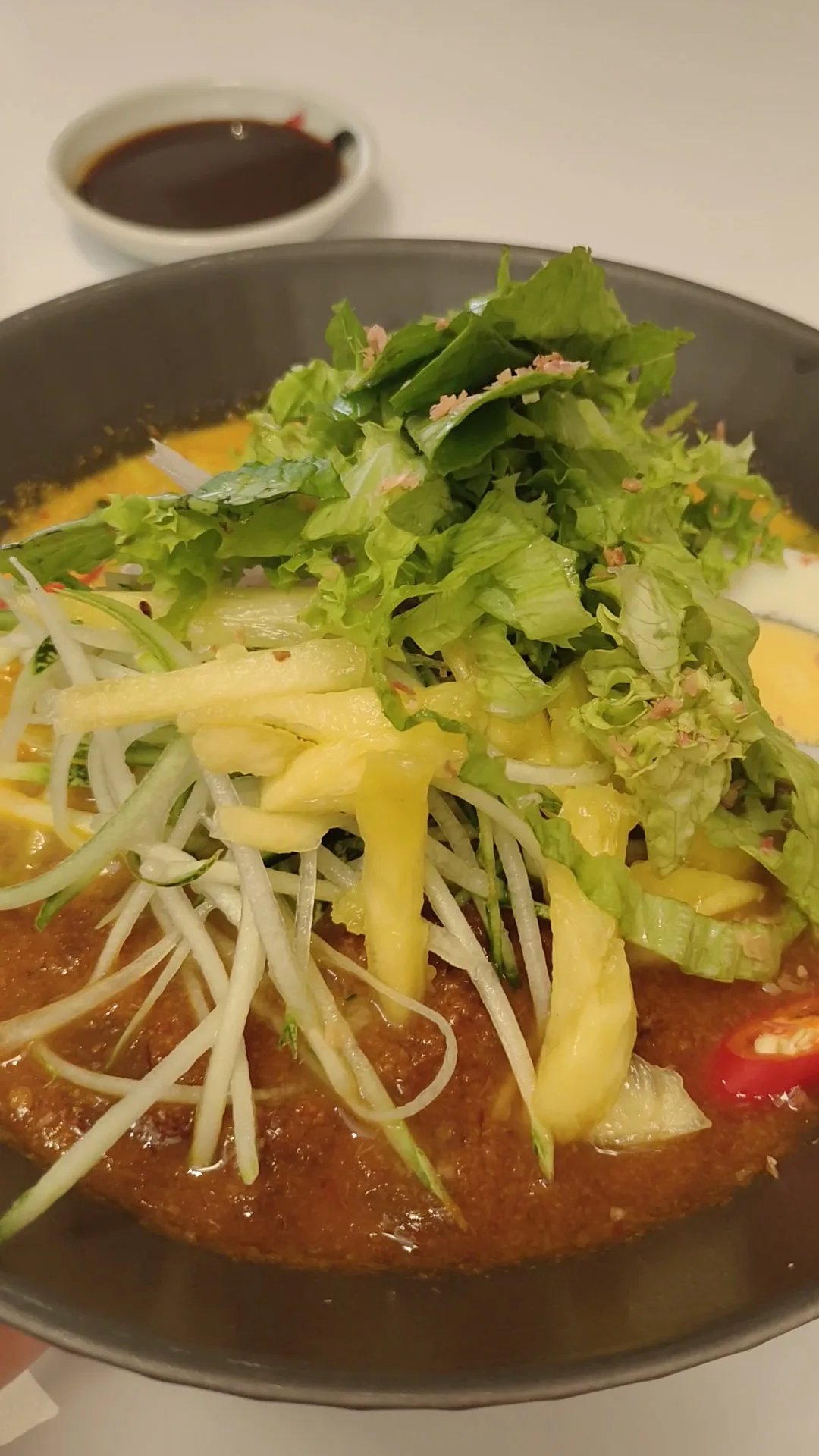 Asam laksa piled with pineapple, cucumber and mint