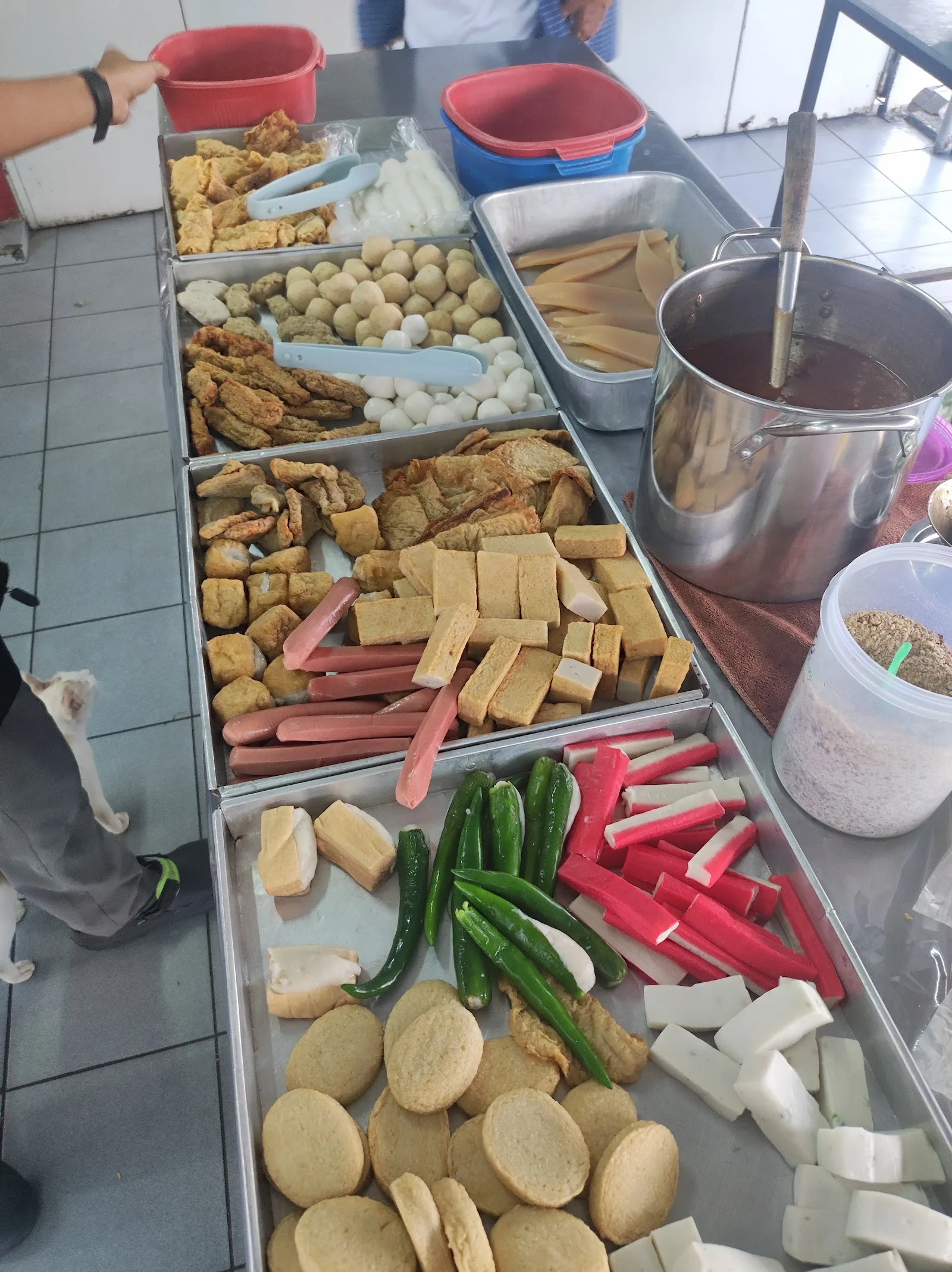Trays of stuffed tofu, fish paste rolls, okra and chillies laid out at the counter