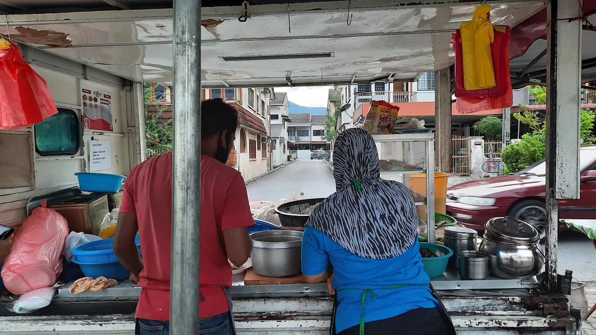 Inside the roadside stall, two cooks at the wok station