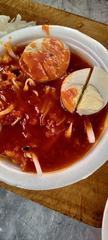 Bowl of rojak mee in thick red sauce with bean sprouts and halved boiled egg
