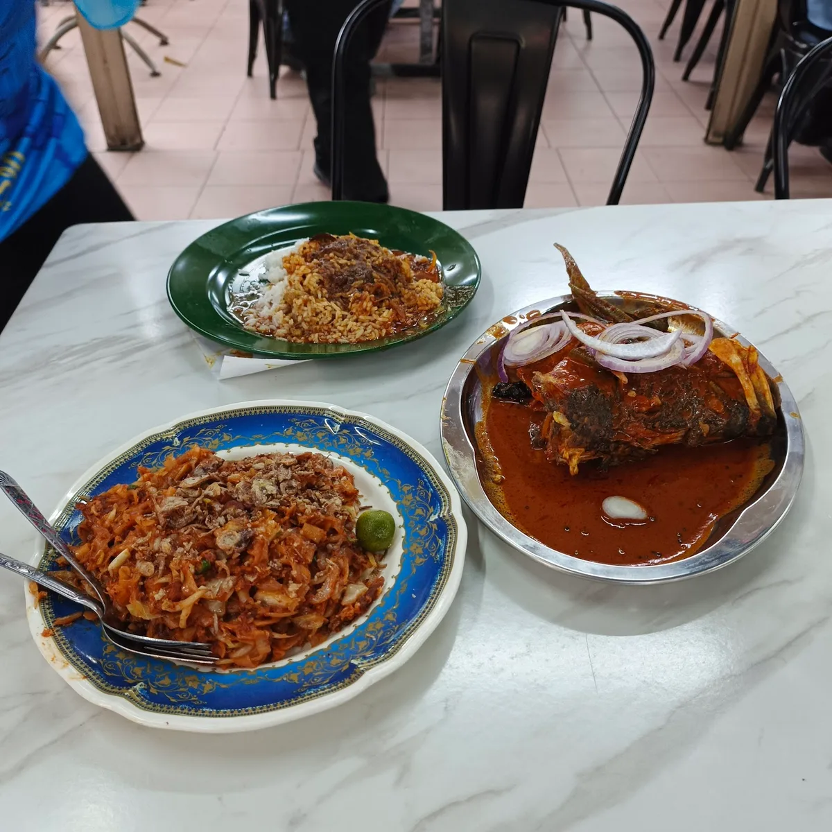 Fish head curry beside two plates of nasi kandar