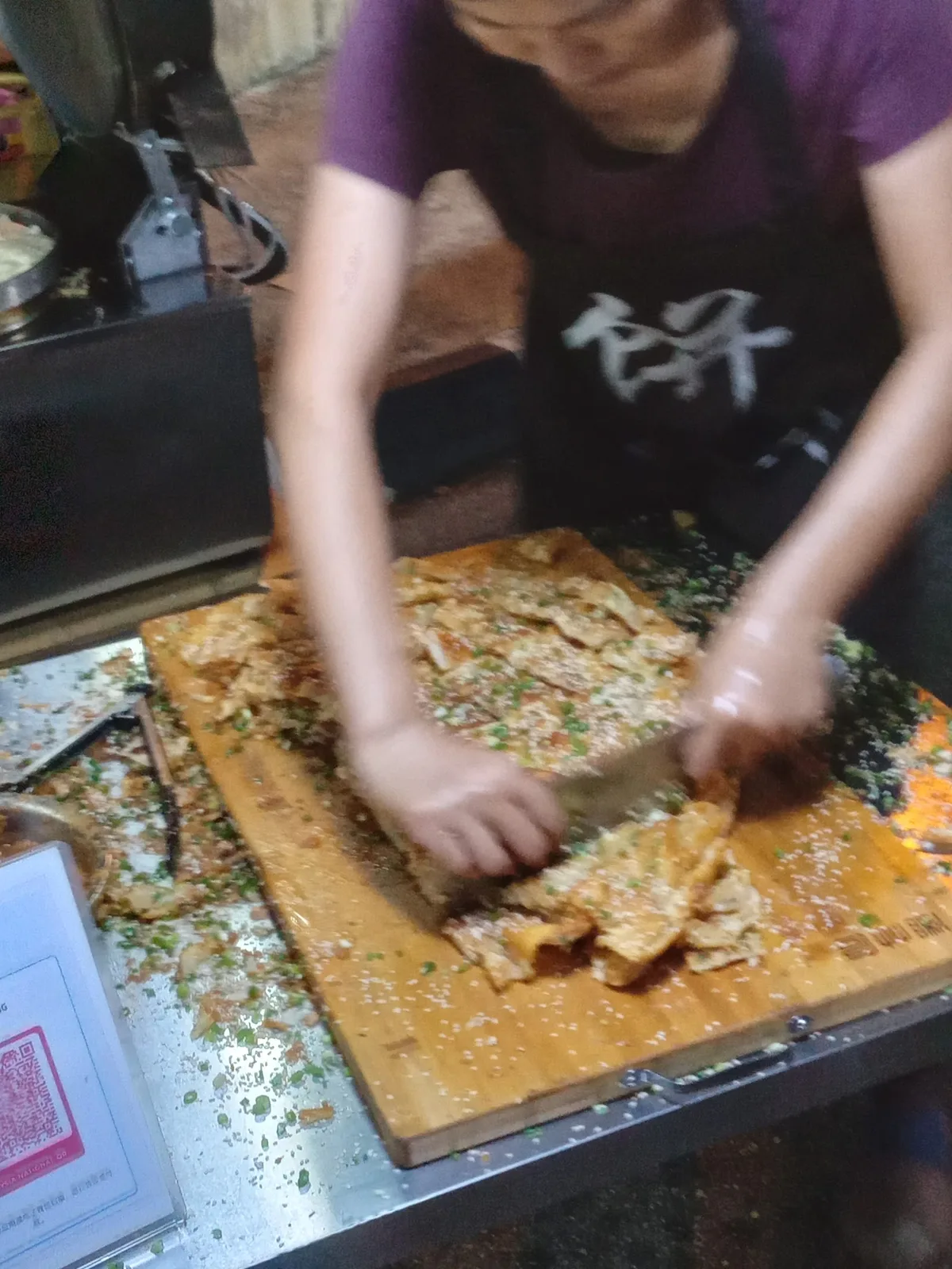 Vendor folding a peanut pancake on a wooden board at a night stall