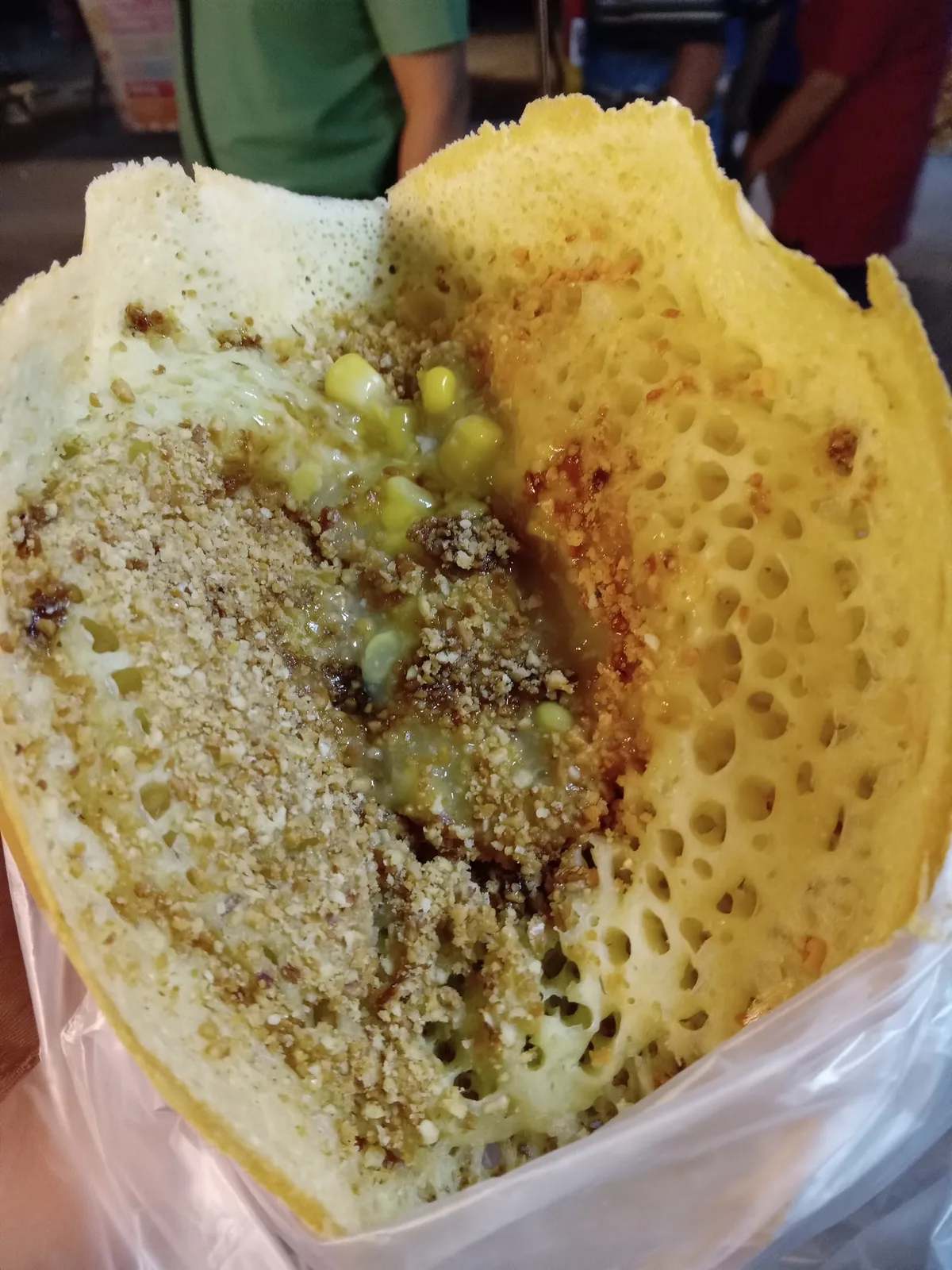 Thick peanut and sweetcorn pancake held in a plastic bag