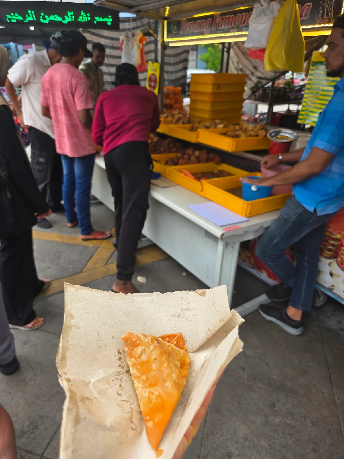 Samosa in hand at the stall counter