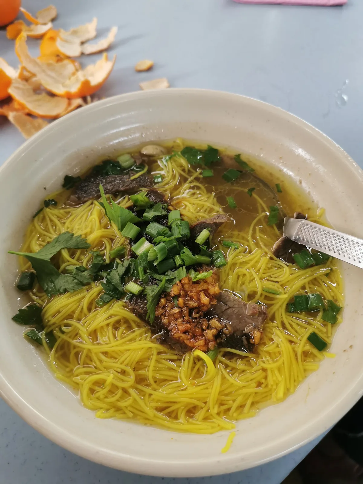 Yellow noodle soup with beef slices, spring onion and fried shallots