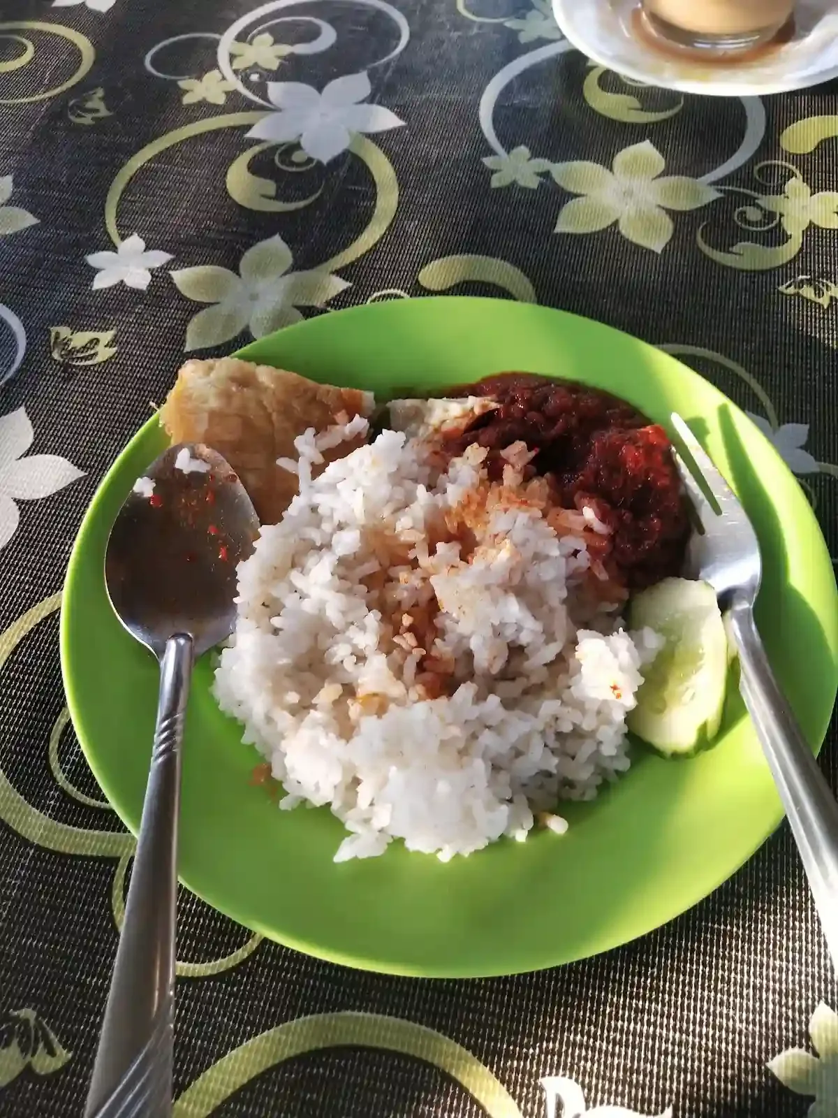Nasi lemak on a green plate with sambal and cucumber
