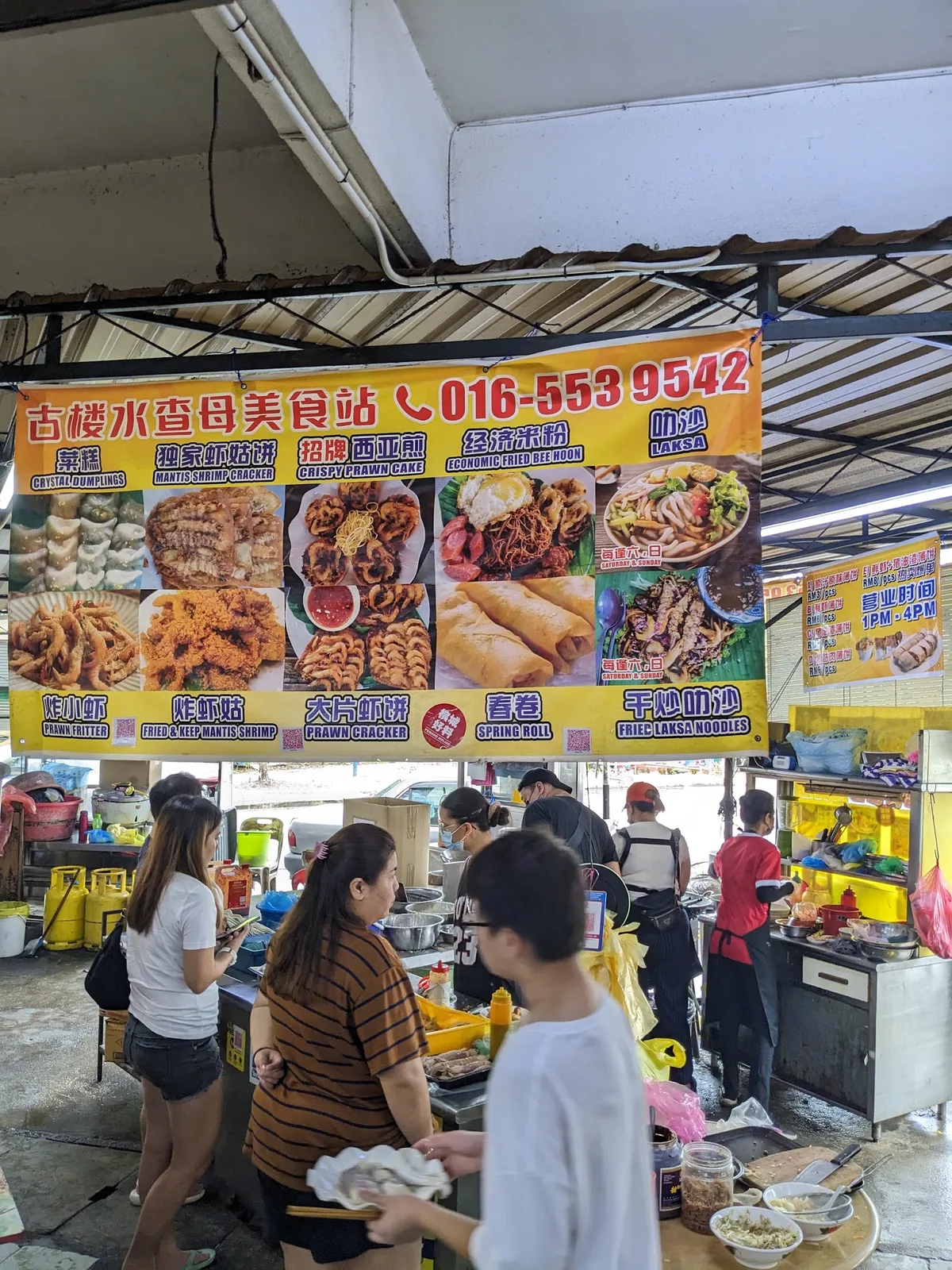 Stall front under the food court roof with customers queueing