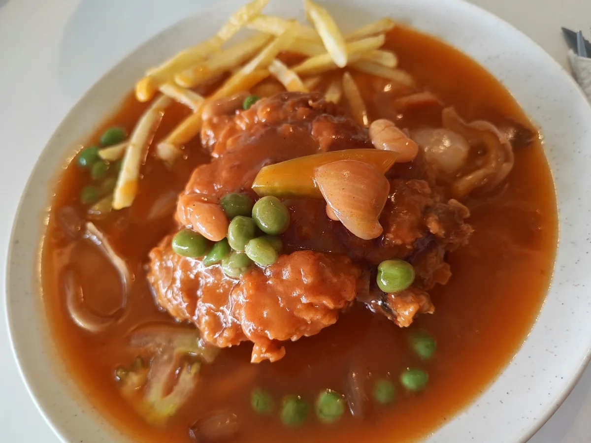 Hainanese chicken chop with gravy, peas and potato chips