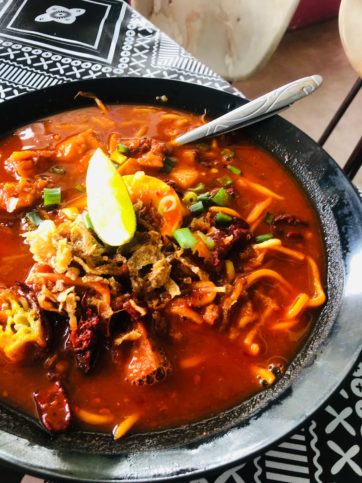 Mee rebus mix with squid, prawn and lime in a black bowl
