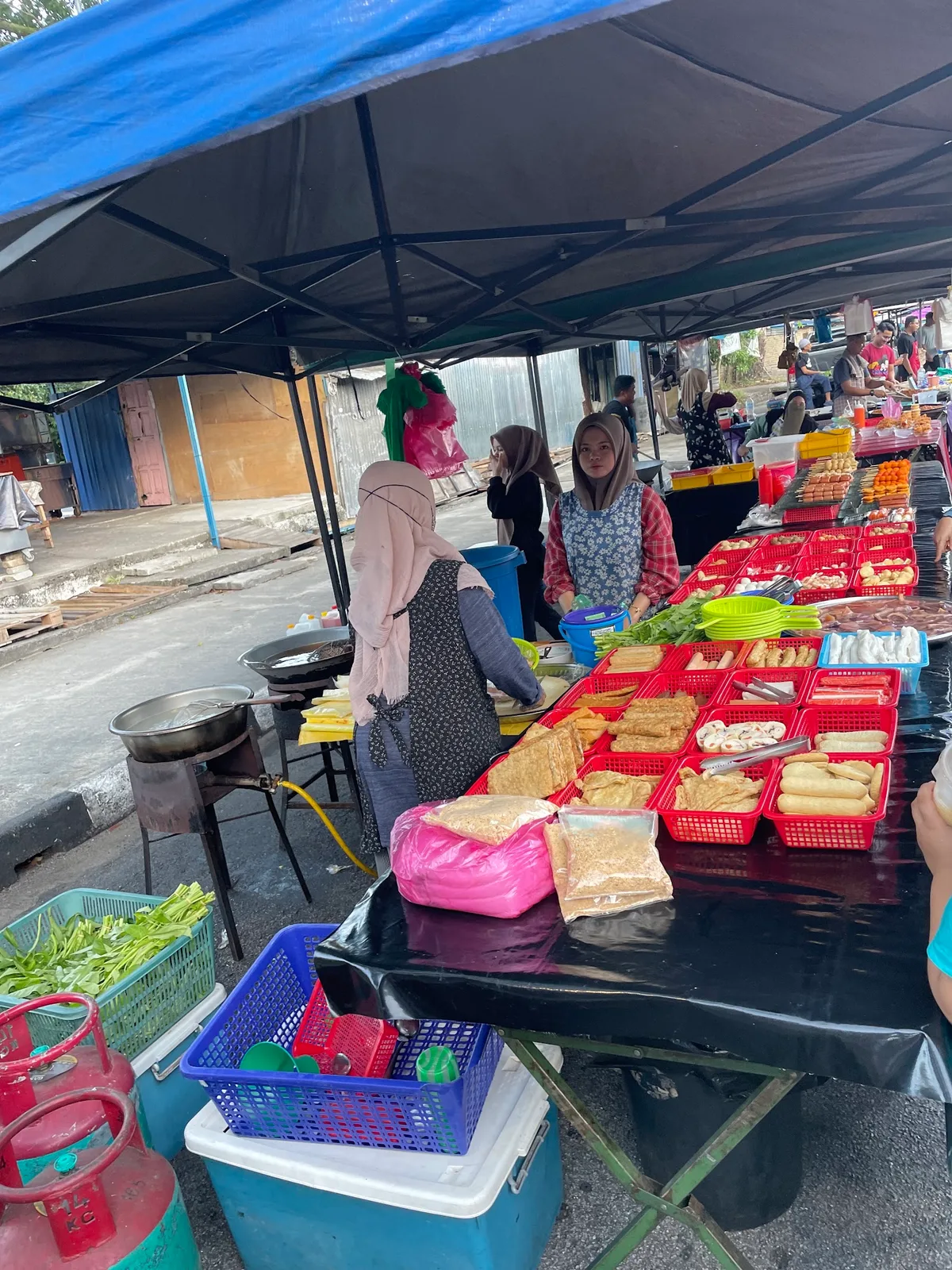 Stall selling fried tofu and kuih from red trays along the market row