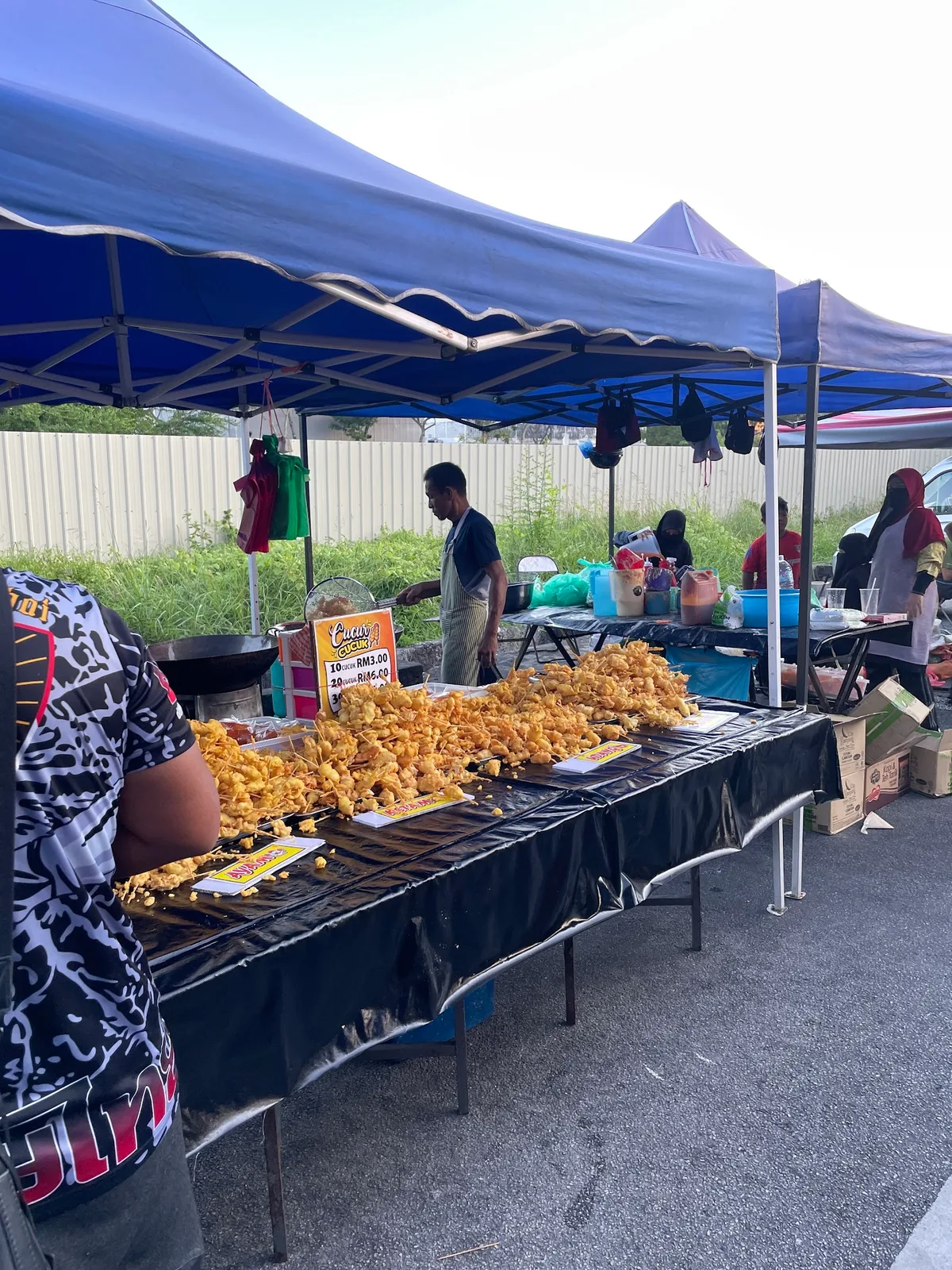 Trays of fried chicken and snacks along a night market table