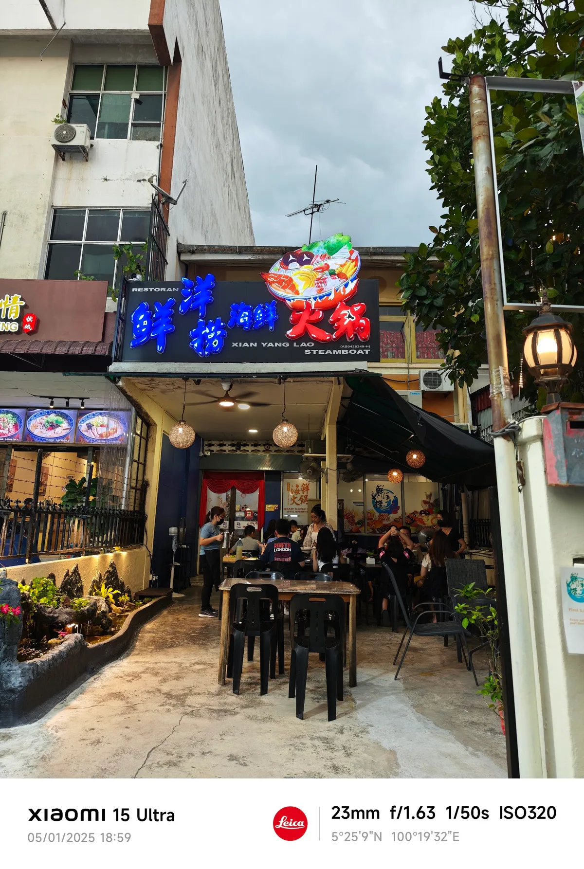 Daytime shopfront with the Xian Yang Lao Steamboat signboard and alfresco tables