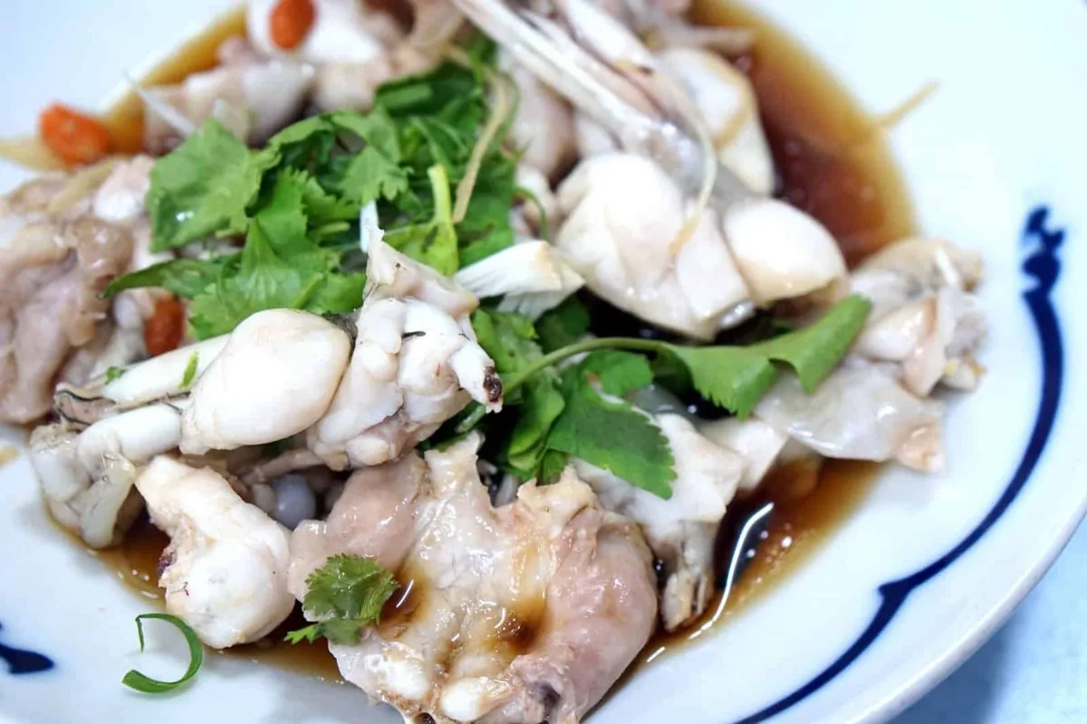 Plate of steamed frog legs with coriander, shredded ginger and goji berries in soy sauce