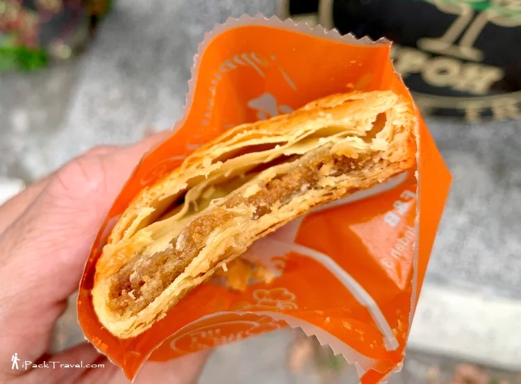 A kaya puff broken open to show the layered pastry and filling